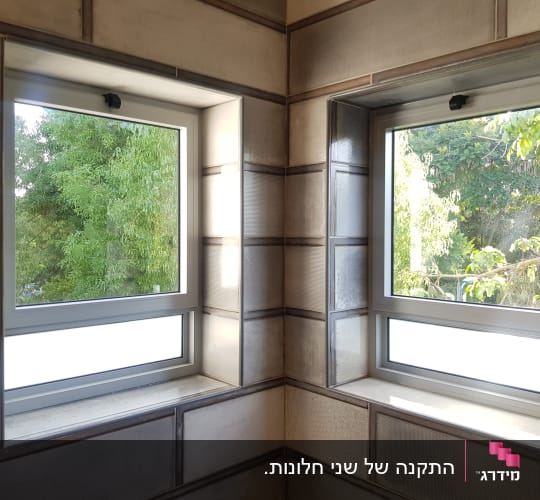 שני חלונות אלומיניום חדשים המותקנים בפינת חדר המשקיף לגינה